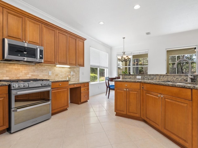 kitchen with dark stone counters, sink, stainless steel appliances, and a notable chandelier