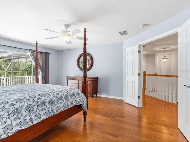 bedroom with hardwood / wood-style floors, ceiling fan, access to exterior, and a textured ceiling