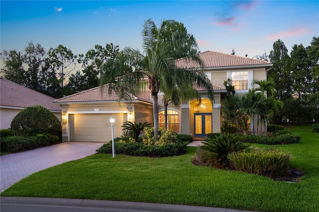 mediterranean / spanish-style home featuring a yard, french doors, and a garage