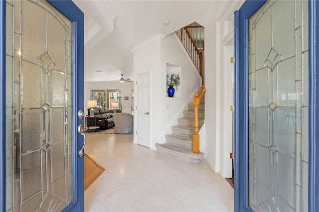 tiled entryway with ceiling fan and ornamental molding