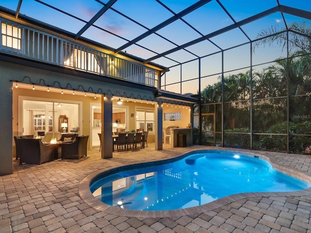 pool at dusk featuring outdoor lounge area, glass enclosure, and a patio area