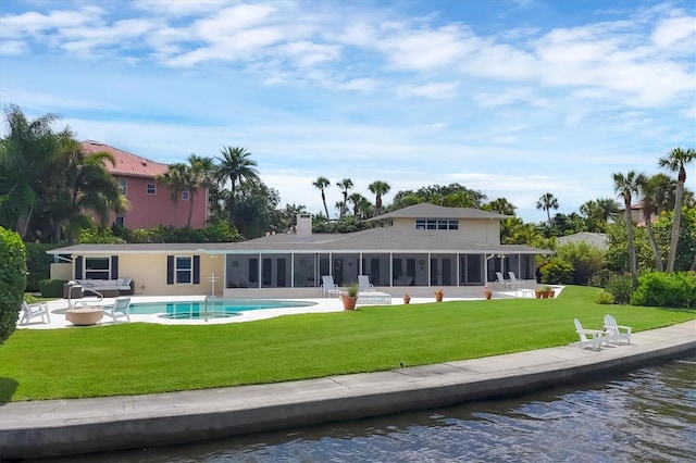 back of property featuring a sunroom, a water view, a lawn, and a patio