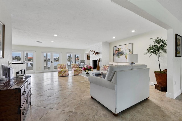 tiled living room with a brick fireplace, a textured ceiling, and french doors