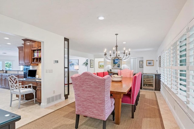 dining space featuring wine cooler, light tile patterned floors, and an inviting chandelier