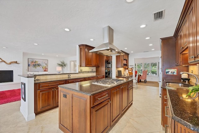 kitchen featuring island exhaust hood, a kitchen island, stainless steel gas stovetop, and sink