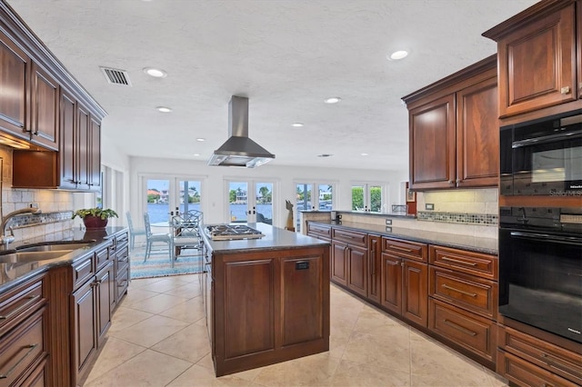 kitchen featuring extractor fan, sink, stainless steel gas cooktop, french doors, and a center island