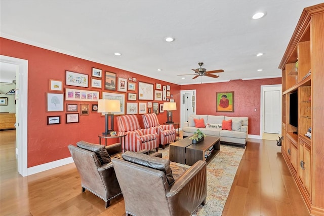 living room featuring ceiling fan, light wood-type flooring, and ornamental molding