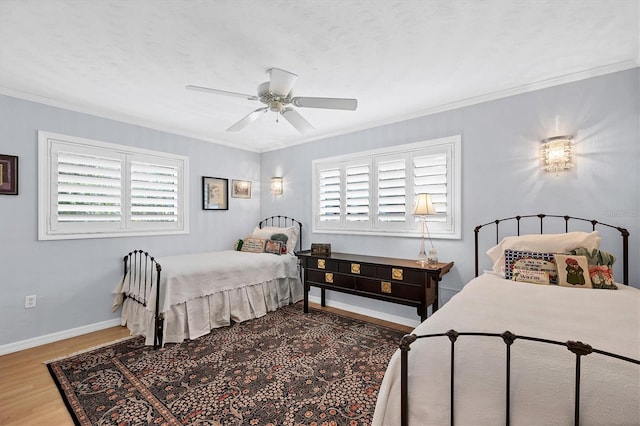 bedroom with ceiling fan, wood-type flooring, multiple windows, and ornamental molding