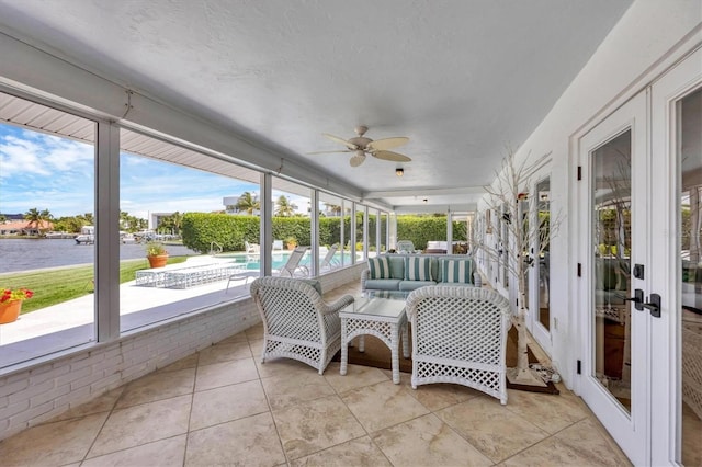 sunroom / solarium featuring ceiling fan, french doors, and a water view