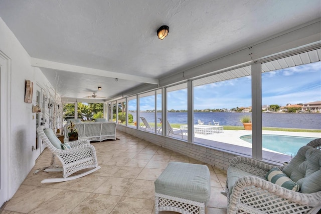 sunroom / solarium featuring ceiling fan and a water view