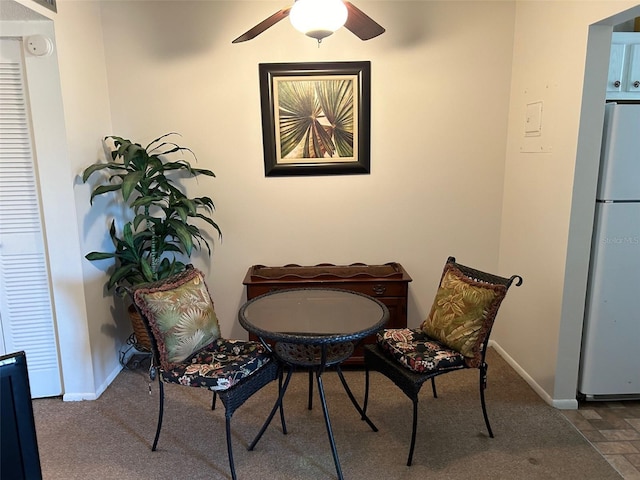 sitting room featuring stone finish floor, ceiling fan, and baseboards