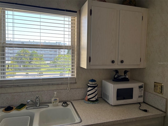 kitchen with light countertops, a sink, and white microwave