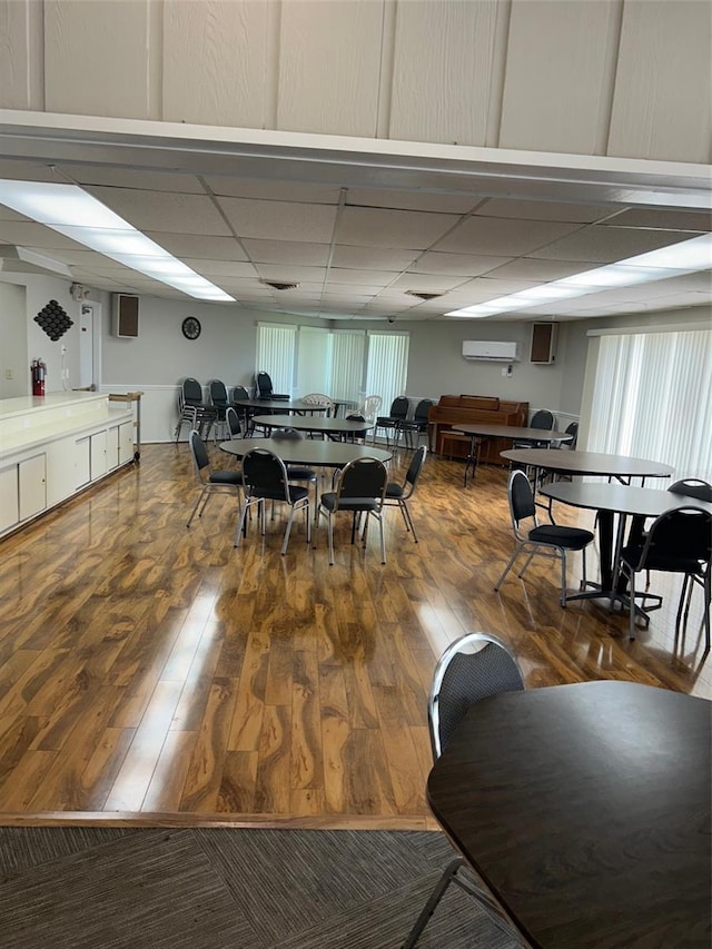 dining space with a healthy amount of sunlight, hardwood / wood-style floors, and a drop ceiling