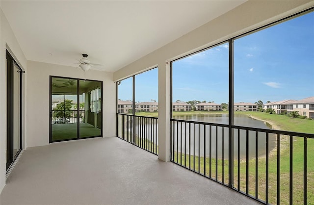 unfurnished sunroom with ceiling fan and a water view