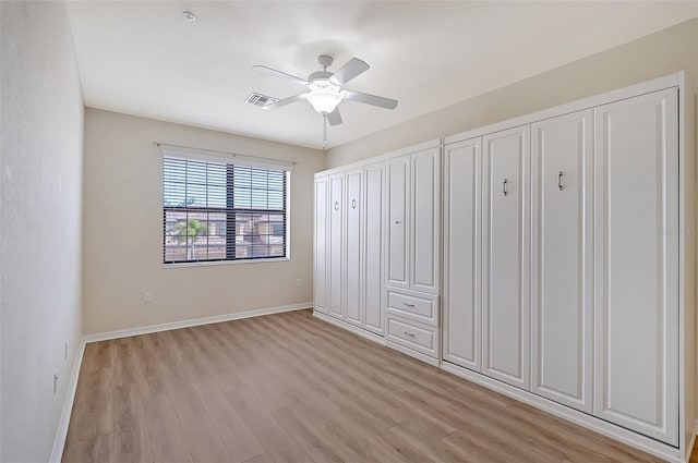 unfurnished bedroom featuring ceiling fan, light hardwood / wood-style flooring, and two closets