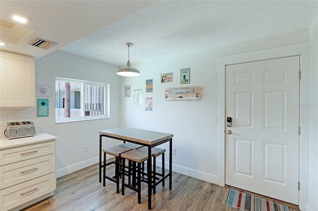 dining area with light hardwood / wood-style floors and a textured ceiling