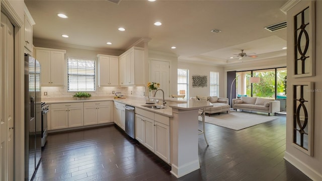 kitchen featuring a peninsula, a sink, white cabinets, open floor plan, and light countertops