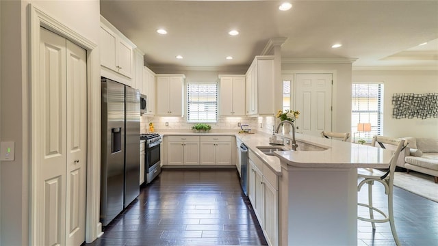 kitchen with open floor plan, stainless steel appliances, a breakfast bar area, and white cabinetry