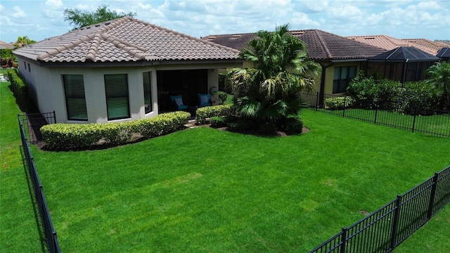 rear view of property with a fenced backyard, a tile roof, a lawn, and stucco siding