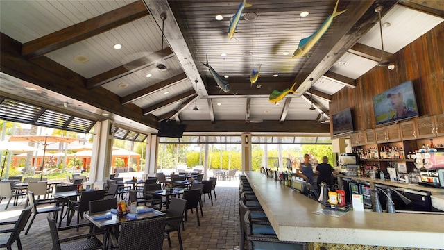 interior space featuring high vaulted ceiling, beam ceiling, brick floor, and wood walls