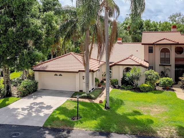 mediterranean / spanish home with a garage, a tile roof, stucco siding, a chimney, and a front yard