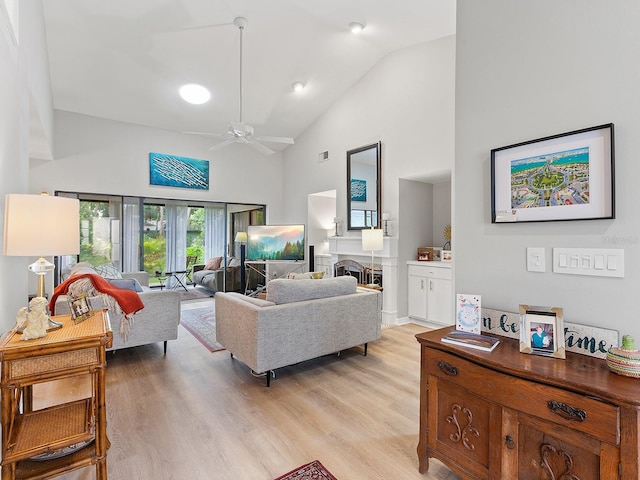 living room with ceiling fan, light hardwood / wood-style flooring, and high vaulted ceiling