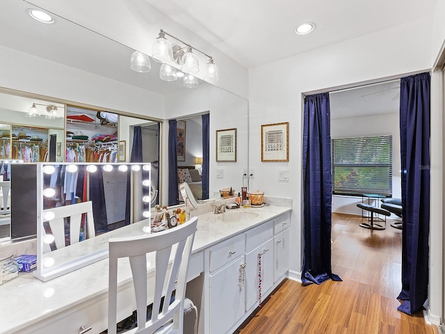 bathroom featuring baseboards, wood finished floors, vanity, and recessed lighting