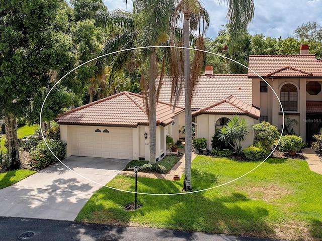 mediterranean / spanish-style home with a tile roof, stucco siding, concrete driveway, an attached garage, and a front lawn