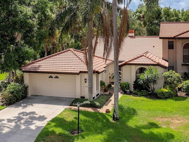 mediterranean / spanish-style home featuring a front yard, a tiled roof, an attached garage, and stucco siding