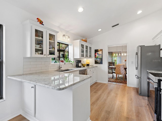 kitchen featuring tasteful backsplash, kitchen peninsula, sink, white cabinetry, and stainless steel appliances