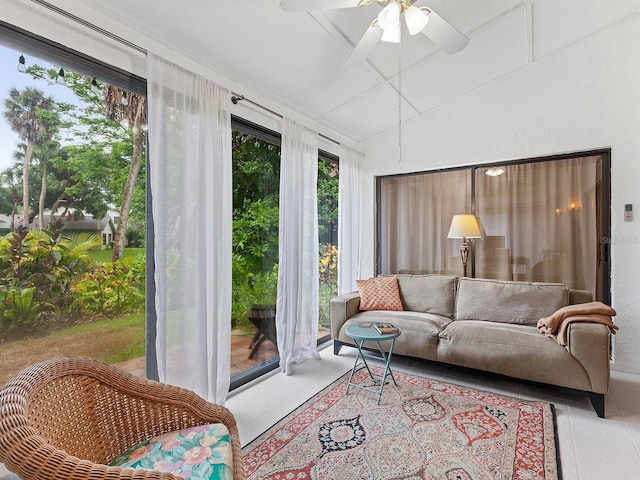 living room with a ceiling fan, lofted ceiling, and light tile patterned floors