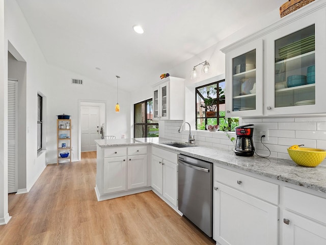 kitchen featuring a peninsula, lofted ceiling, tasteful backsplash, a sink, and dishwasher