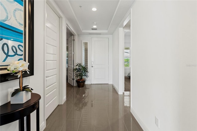 hall with tile patterned flooring and a tray ceiling