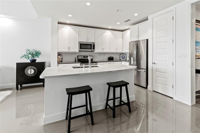 kitchen with appliances with stainless steel finishes, white cabinets, and light stone countertops