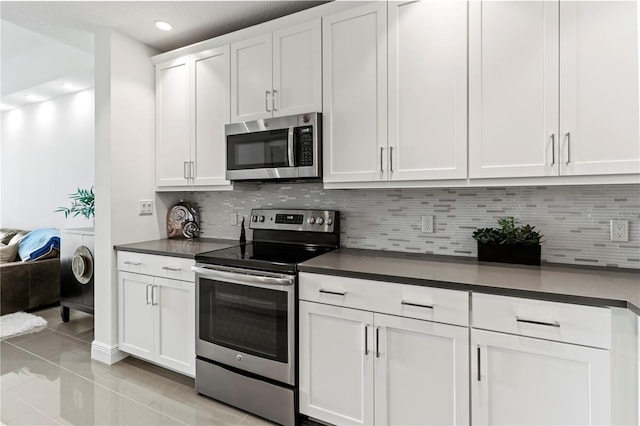 kitchen featuring appliances with stainless steel finishes, white cabinetry, decorative backsplash, and light tile patterned floors