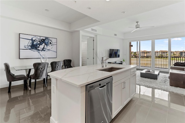 kitchen with white cabinets, light stone counters, ceiling fan, an island with sink, and stainless steel dishwasher