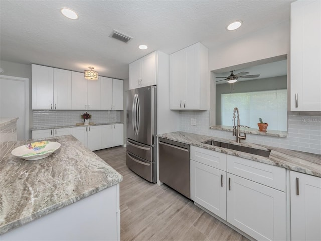 kitchen featuring white cabinetry, sink, stainless steel appliances, and a textured ceiling