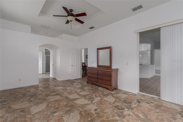 unfurnished bedroom with a raised ceiling, connected bathroom, and ceiling fan