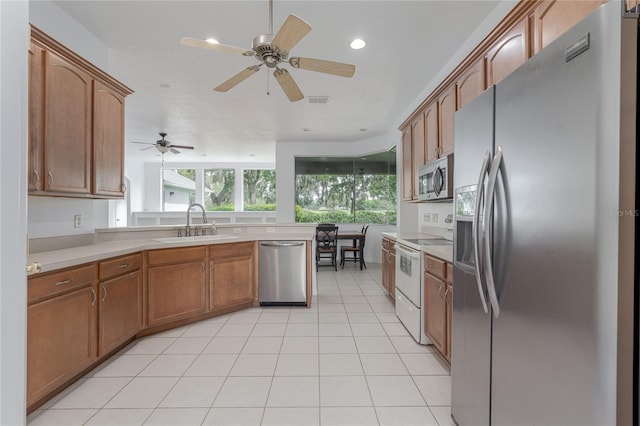 kitchen with appliances with stainless steel finishes, light tile patterned floors, ceiling fan, and sink