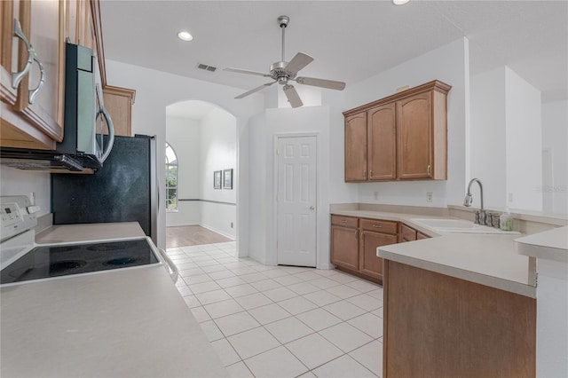 kitchen with kitchen peninsula, ceiling fan, sink, light tile patterned floors, and electric range