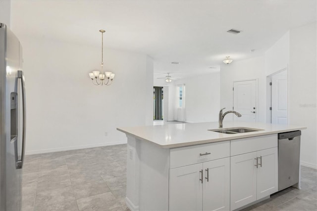 kitchen featuring appliances with stainless steel finishes, ceiling fan with notable chandelier, sink, a center island with sink, and white cabinetry