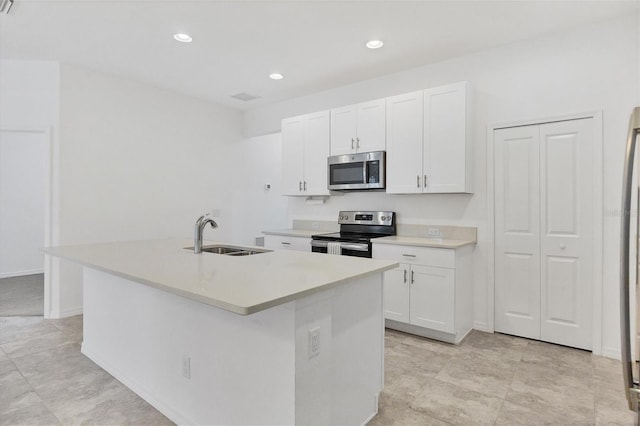 kitchen with appliances with stainless steel finishes, an island with sink, white cabinetry, and sink