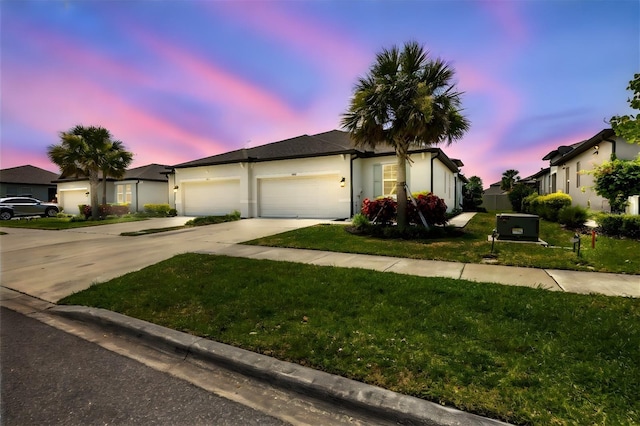 ranch-style house featuring a garage, a front yard, driveway, and stucco siding