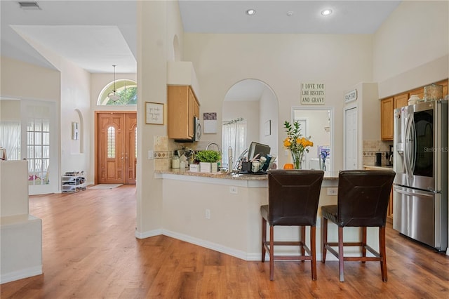 kitchen featuring a kitchen bar, appliances with stainless steel finishes, a wealth of natural light, and hardwood / wood-style floors