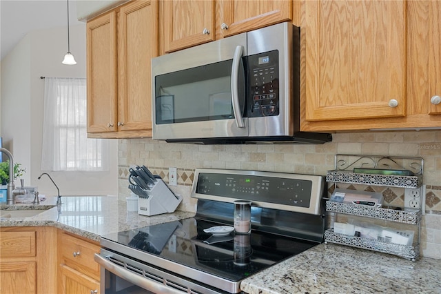 kitchen with light stone countertops, sink, appliances with stainless steel finishes, and tasteful backsplash