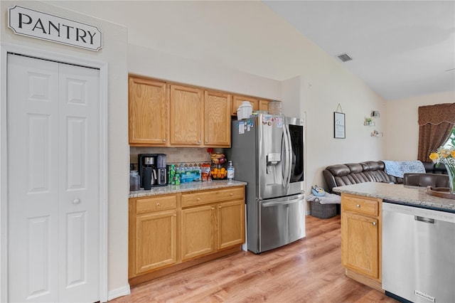 kitchen featuring backsplash, light stone counters, stainless steel appliances, and light hardwood / wood-style floors