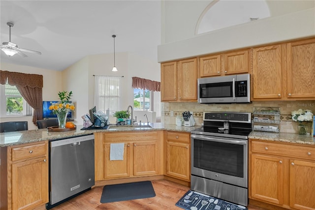 kitchen featuring backsplash, light stone counters, sink, and appliances with stainless steel finishes