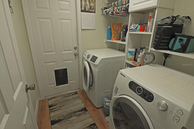 laundry room with cabinets, hardwood / wood-style floors, and washing machine and clothes dryer