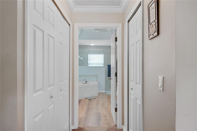 hall with light wood-type flooring and crown molding