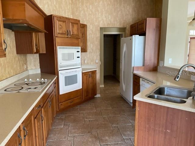 kitchen with white appliances, sink, and custom exhaust hood